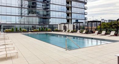 Expansive outdoor swimming pool on the rooftop with lounge chairs and surrounding city views at SoNo East Apartments in Chicago