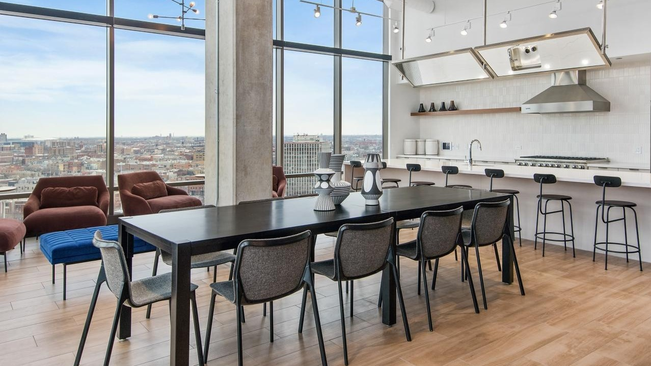 An expansive dining area at Spoke Apartments in Chicago, with a large table and panoramic city views
