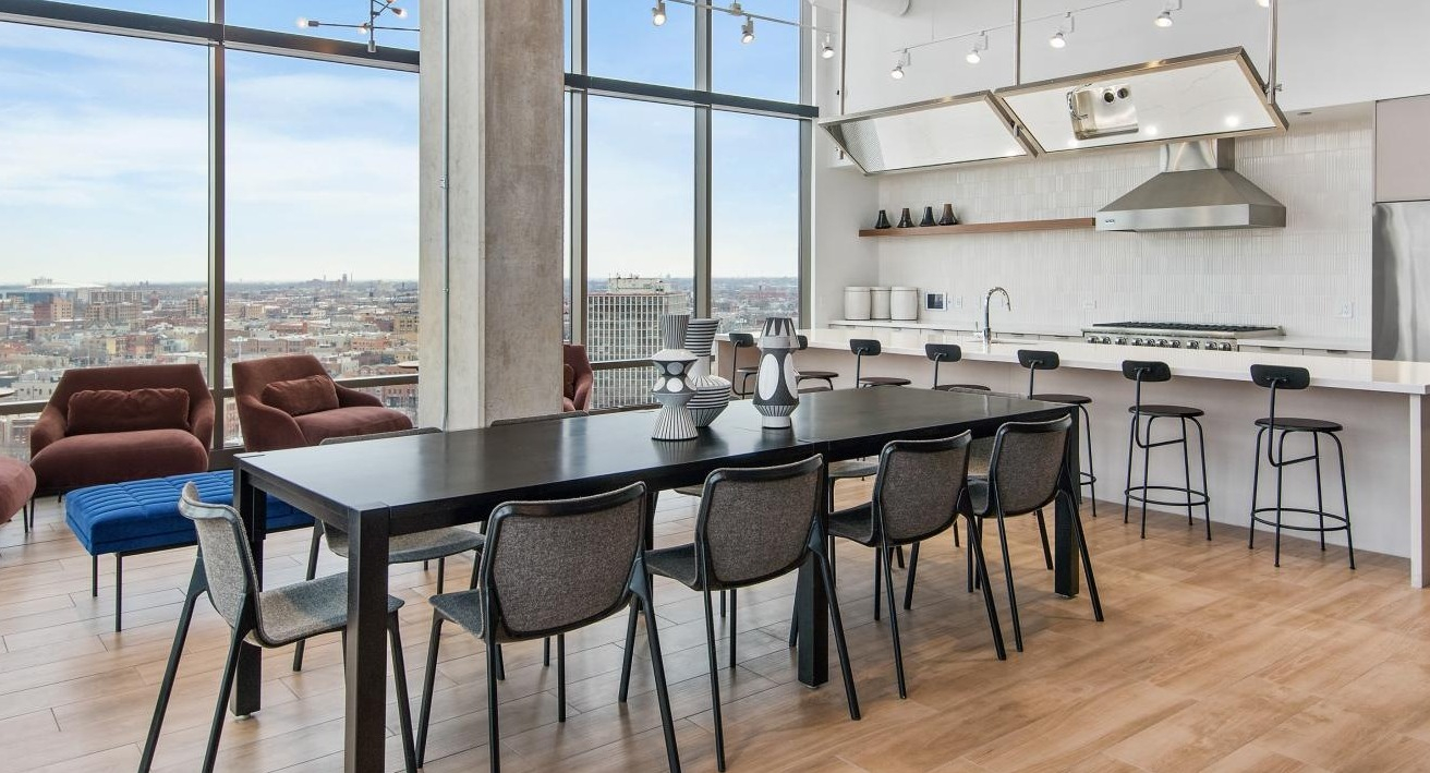 An expansive dining area at Spoke Apartments in Chicago, with a large table and panoramic city views