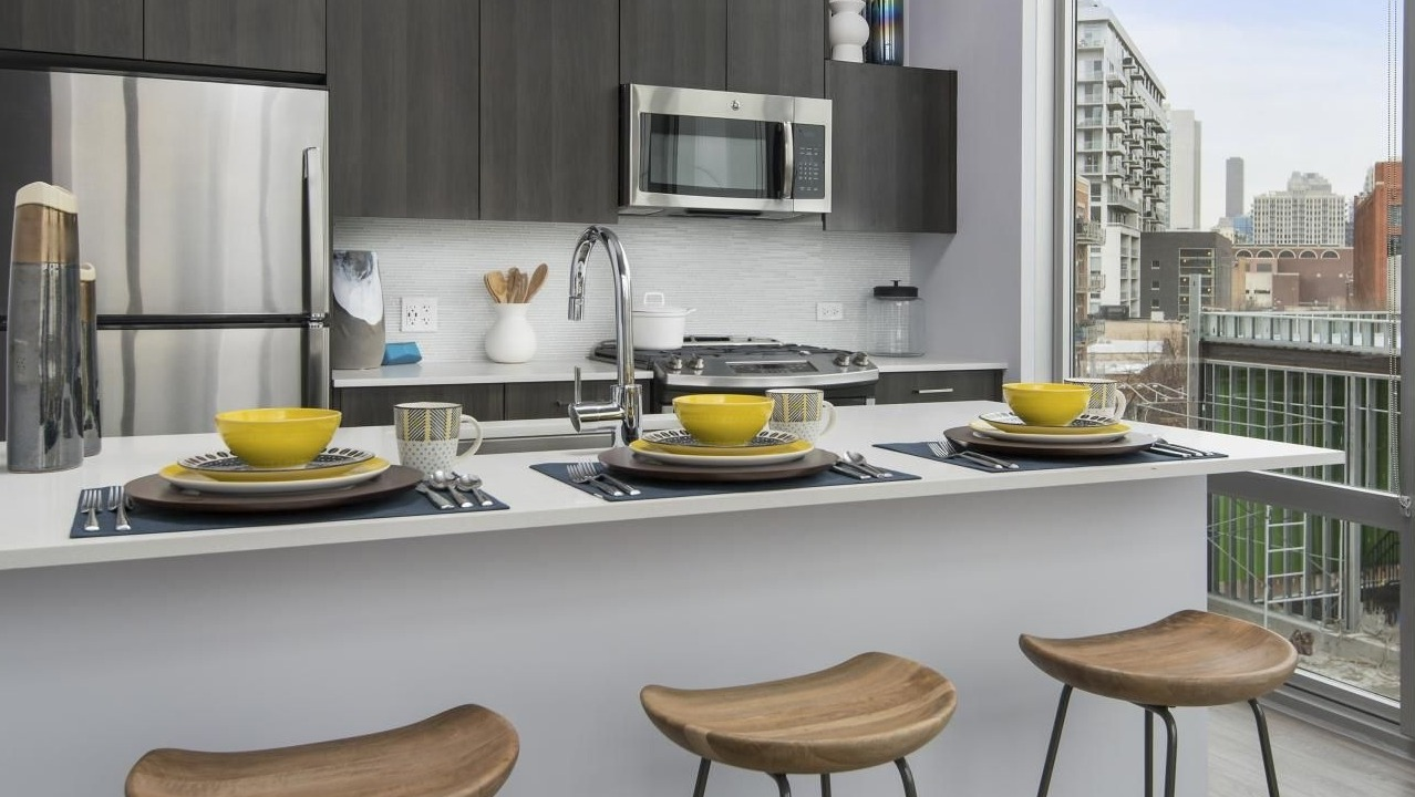 A modern kitchen at Spoke Apartments in Chicago, offering great city views from large windows and counter seating