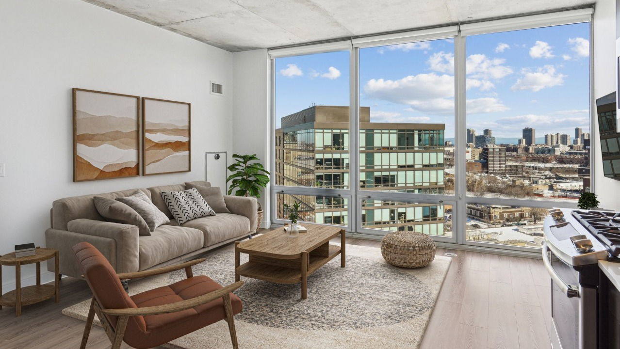 A modern living room at Spoke Apartments in Chicago, featuring city views from large windows and comfortable furniture