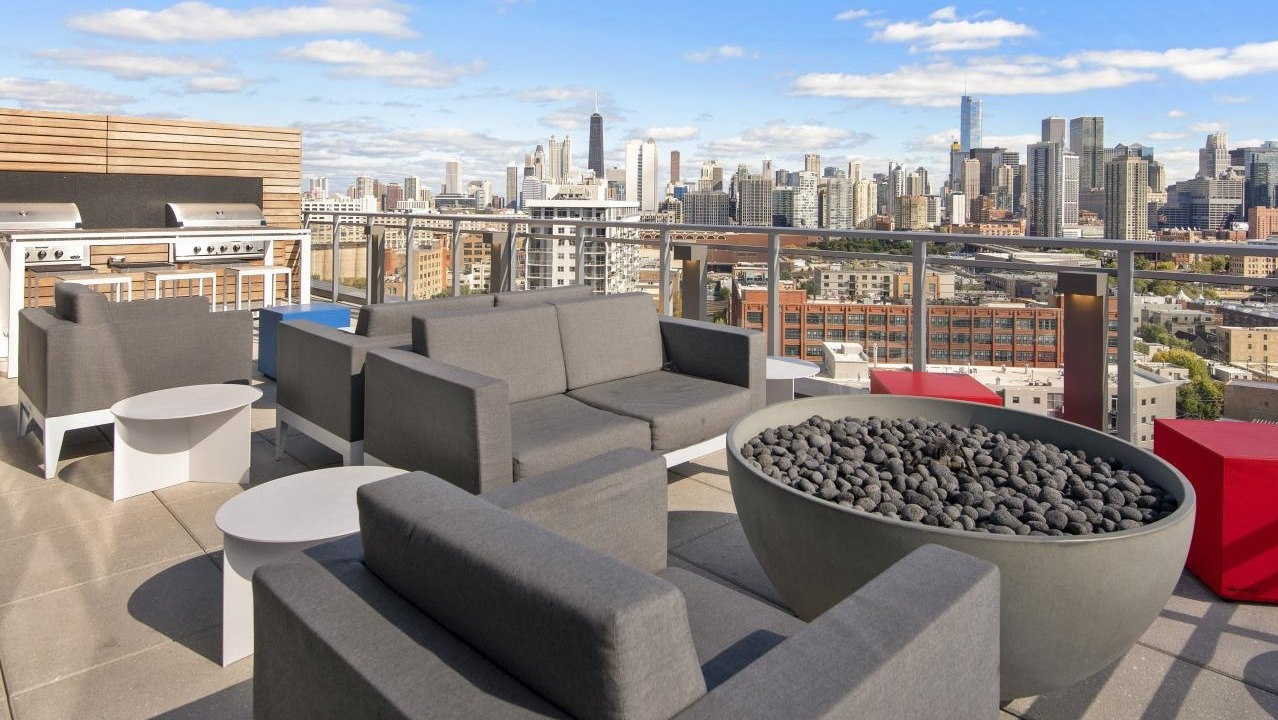 A rooftop lounge at Spoke Apartments in Chicago, complete with comfortable seating, a fire pit, and stunning city views