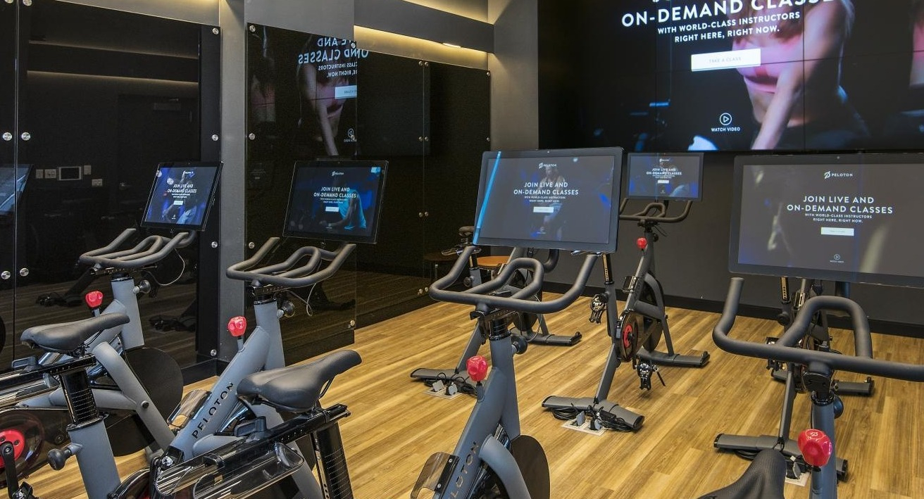 A state-of-the-art fitness center at Spoke Apartments in Chicago, featuring multiple Peloton bikes and large screens