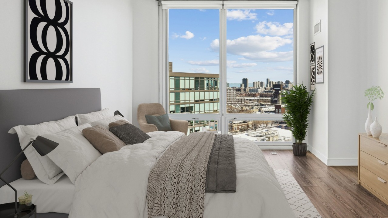 A stylish bedroom at Spoke Apartments in Chicago, with a large window offering city views and contemporary decor