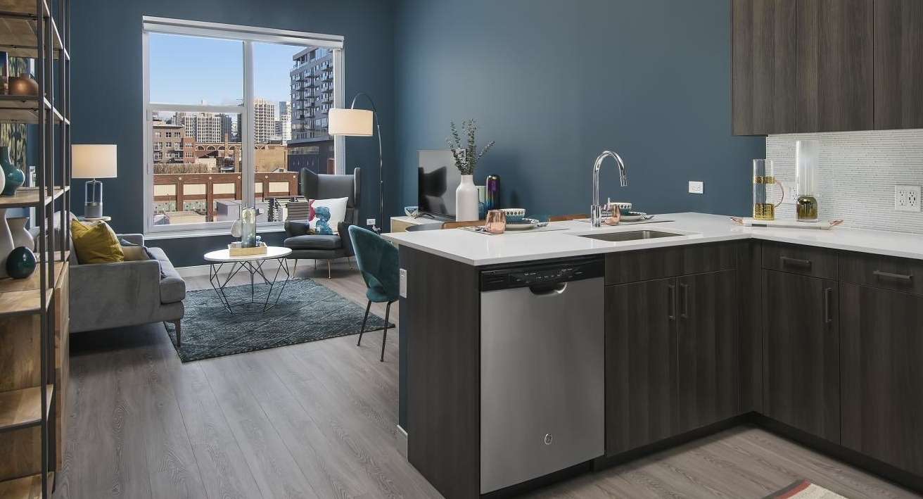 A stylish kitchen and living area at Spoke Apartments in Chicago, with dark cabinetry and a striking blue wall