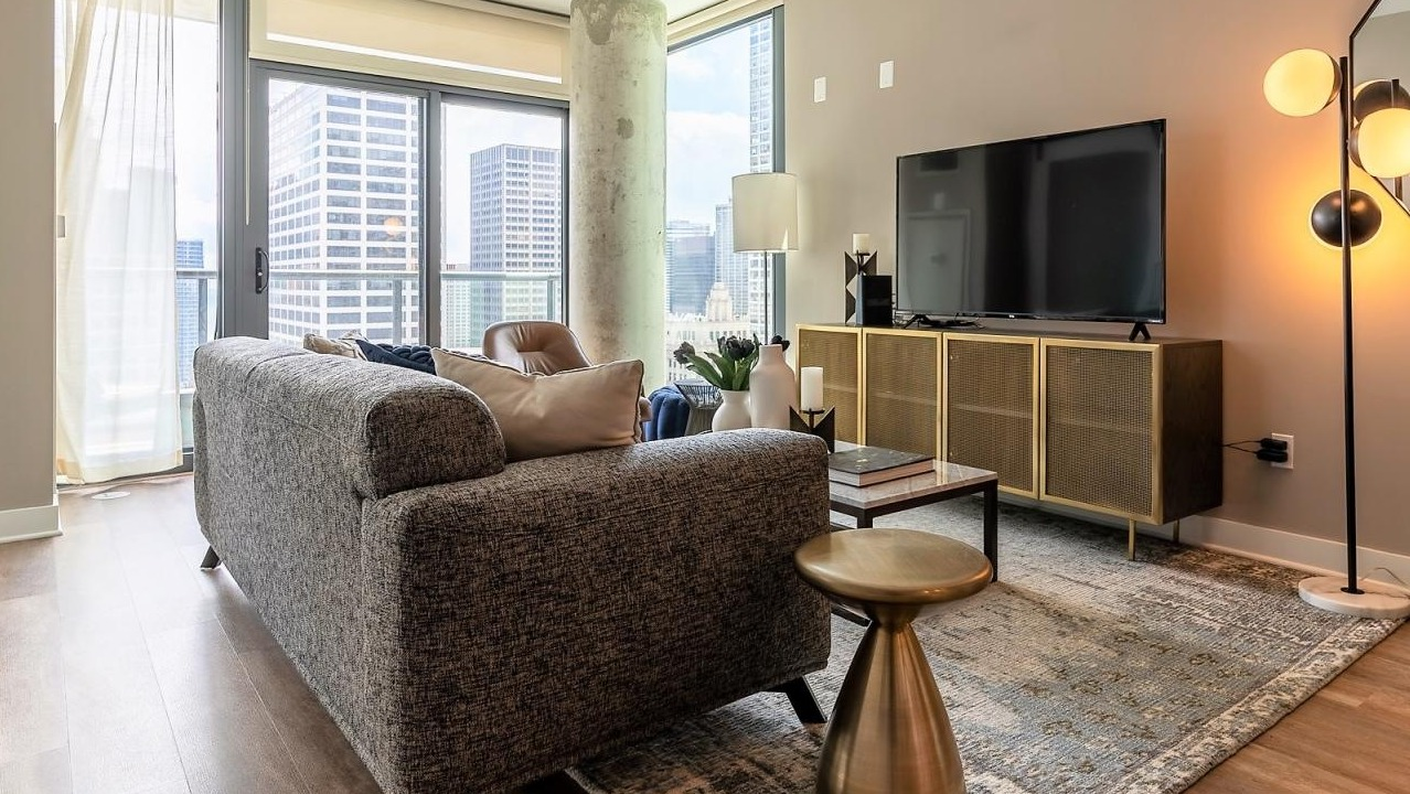 Stylish living room with a comfortable sofa, modern decor, and expansive windows offering picturesque city views at State and Grand Apartments in Chicago