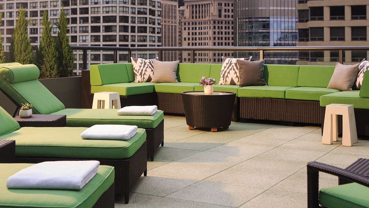 Inviting rooftop patio with plush green lounge seating and city skyline views, perfect for relaxation at State and Grand Apartments in Chicago