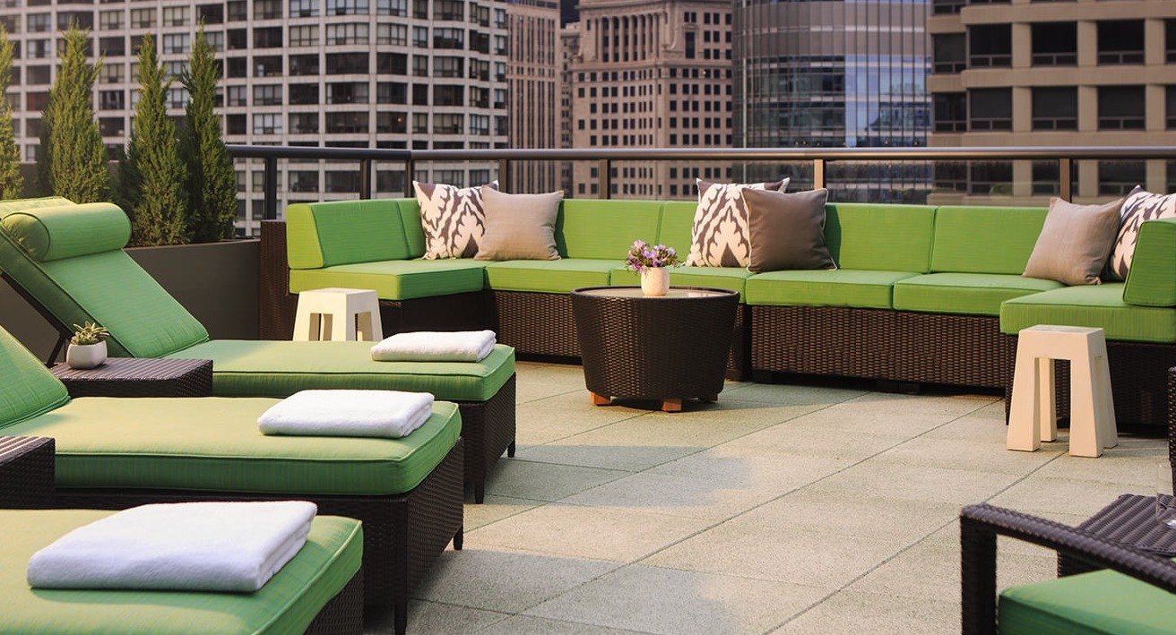 Inviting rooftop patio with plush green lounge seating and city skyline views, perfect for relaxation at State and Grand Apartments in Chicago