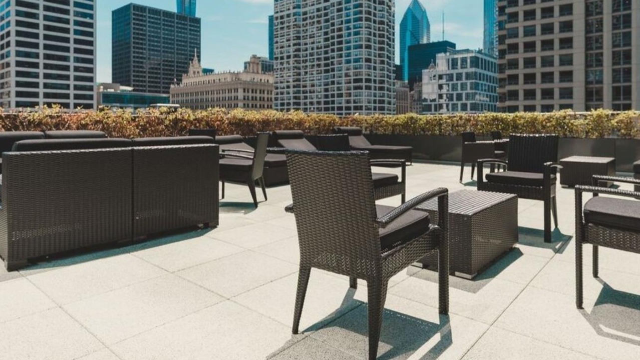 Expansive rooftop terrace with modern black outdoor furniture and panoramic views of the Chicago cityscape at State and Grand Apartments in Chicago