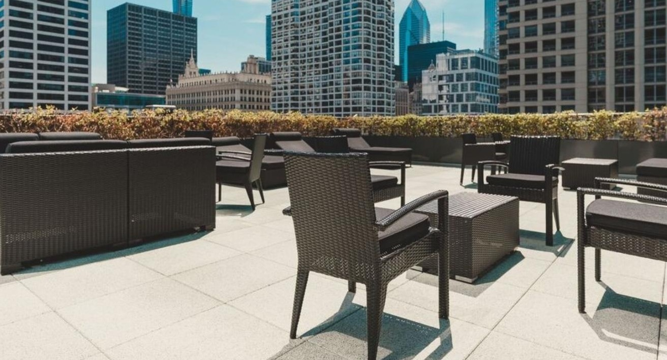 Expansive rooftop terrace with modern black outdoor furniture and panoramic views of the Chicago cityscape at State and Grand Apartments in Chicago