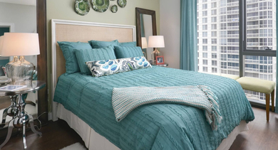 Bright and inviting bedroom at State & Chestnut in Chicago, featuring a comfortable bed, light green walls, and large windows with urban views