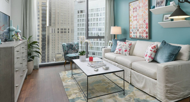 Vibrant living room at State & Chestnut in Chicago, featuring a white sofa, turquoise accent wall, and large windows with city views