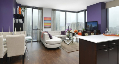 Spacious open-concept living area at State & Chestnut in Chicago, featuring a white sectional sofa, dining table, and purple accent walls