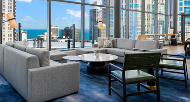 Panoramic resident lounge at State & Chestnut in Chicago, featuring modern sofas, accent chairs, and floor-to-ceiling windows with sweeping city views