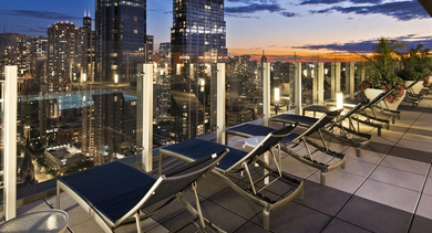 Stunning rooftop deck at State & Chestnut in Chicago at night, featuring lounge chairs and breathtaking city skyline views