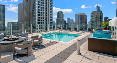 Luxurious rooftop pool deck at State & Chestnut in Chicago, featuring a refreshing swimming pool, fire pit, and comfortable lounge seating with city views