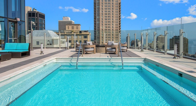 Inviting rooftop swimming pool at State & Chestnut in Chicago, surrounded by comfortable lounges and offering spectacular skyline views