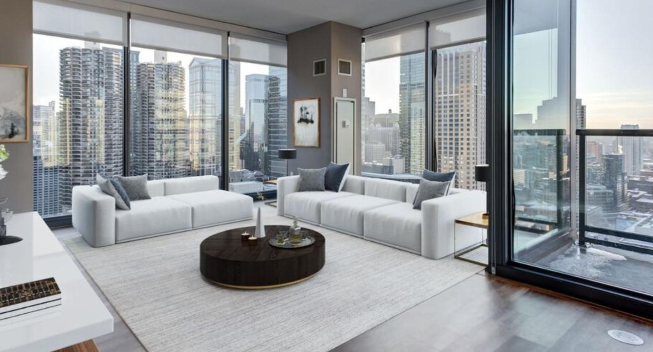 Expansive living room at State and Grand Apartments in Chicago, featuring white sofas, a stylish coffee table, and panoramic city views