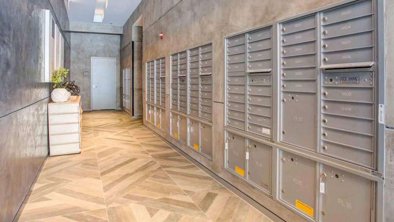 Secure and well-lit mail room at State and Grand Apartments in Chicago, featuring individual mailboxes and package lockers