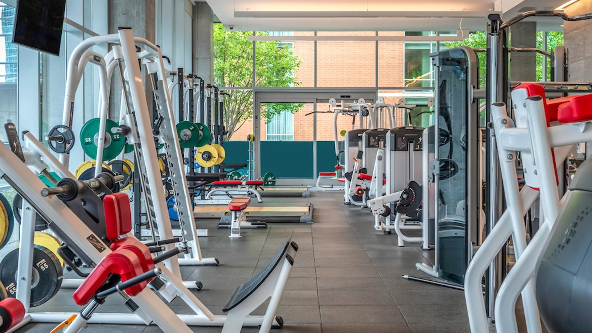 Spacious strength-training gym with free weights, benches, and advanced machines at Optima Signature apartments in Chicago