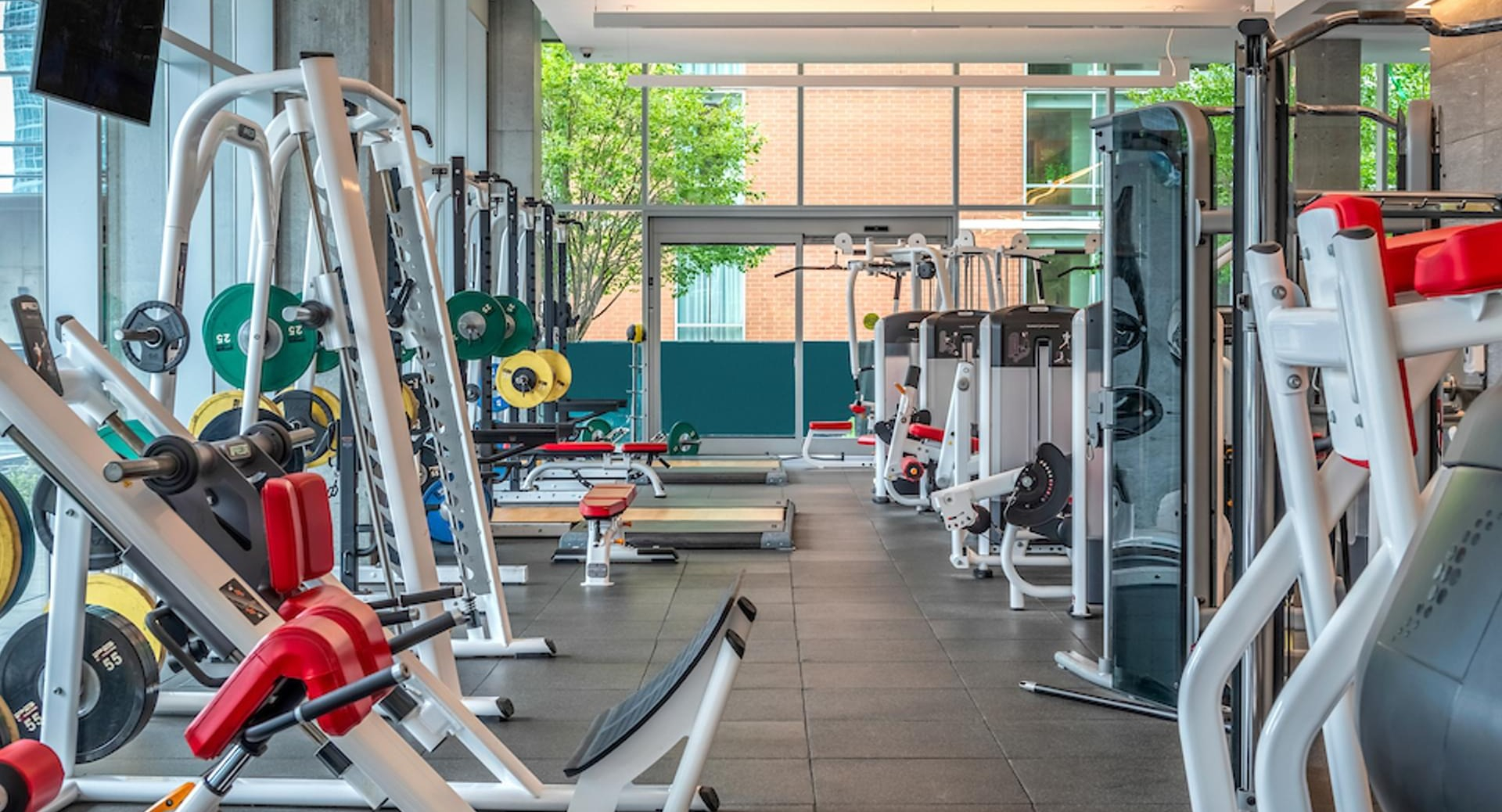 Spacious strength-training gym with free weights, benches, and advanced machines at Optima Signature apartments in Chicago
