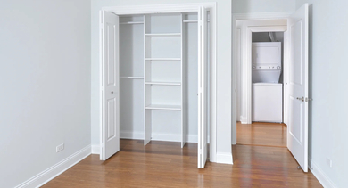 Cozy bedroom featuring hardwood floors and an open closet, ready for personalized decor at The Aberdeen West Loop Luxury Apartments