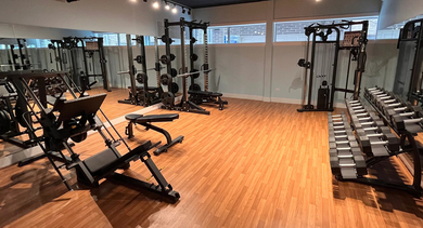 Well-equipped fitness center weights area with various machines and dumbbells at The Aberdeen West Loop Luxury Apartments
