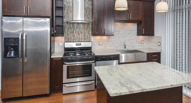 Spacious modern kitchen with dark cabinets, stainless steel appliances, and a large central island at The Aberdeen West Loop Luxury Apartments
