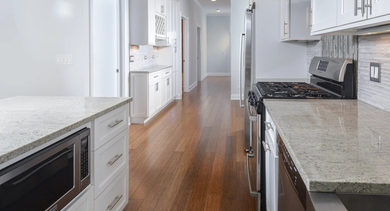 View from a modern kitchen looking down a hallway with hardwood floors and bright lighting in The Aberdeen West Loop Luxury Apartments