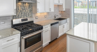 Modern kitchen with white cabinets, stainless steel appliances, and a stylish tiled backsplash at The Aberdeen West Loop Luxury Apartments