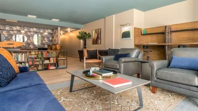 Cozy reading nook and lounge at The Alfred Apartments in Chicago, with a blue sofa, bookshelves, and comfortable armchairs