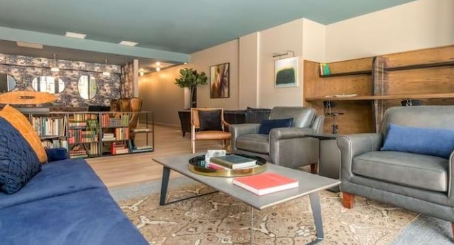 Cozy reading nook and lounge at The Alfred Apartments in Chicago, with a blue sofa, bookshelves, and comfortable armchairs