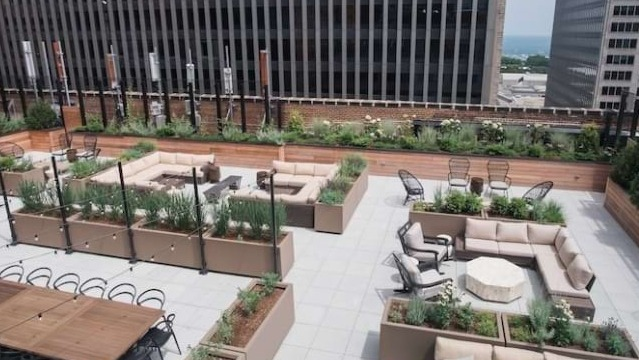 Expansive rooftop terrace at The Alfred Apartments in Chicago, featuring multiple seating areas, fire pits, and city views