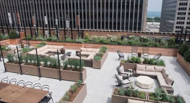 Expansive rooftop terrace at The Alfred Apartments in Chicago, featuring multiple seating areas, fire pits, and city views