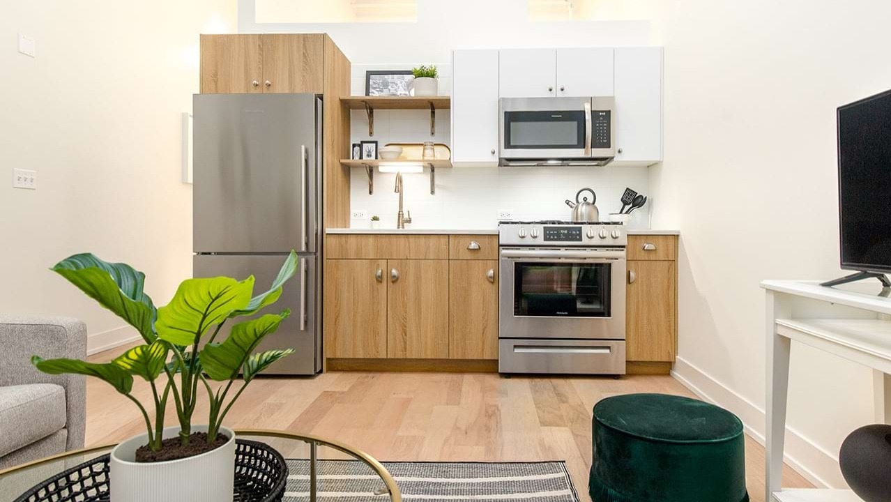 Open kitchen and living space at The Alfred Apartments in Chicago, with a modern kitchen, sofa, and television