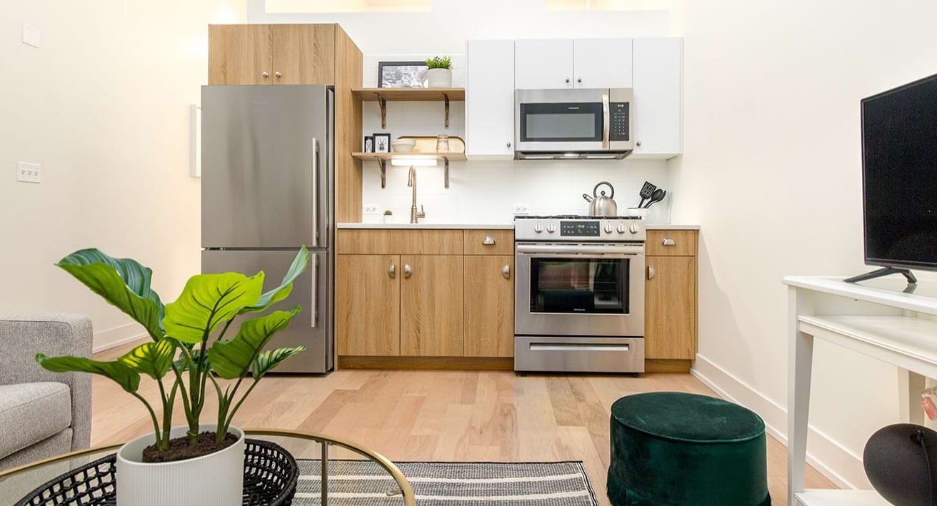 Open kitchen and living space at The Alfred Apartments in Chicago, with a modern kitchen, sofa, and television