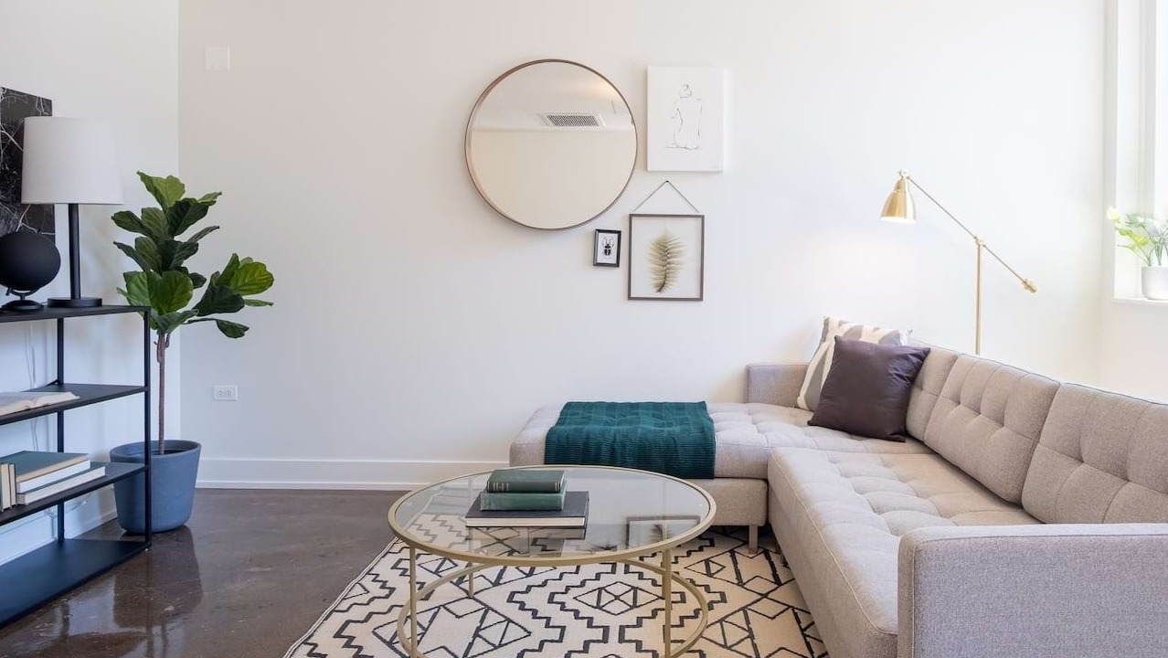 Modern living room at The Alfred Apartments in Chicago, featuring a comfortable sectional sofa, geometric rug, and stylish decor