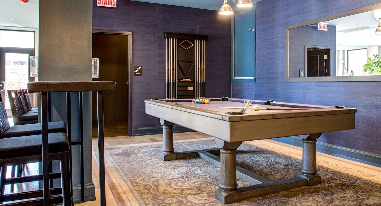 Resident game room at The Alfred Apartments in Chicago, featuring a billiards table, high-top seating, and stylish decor