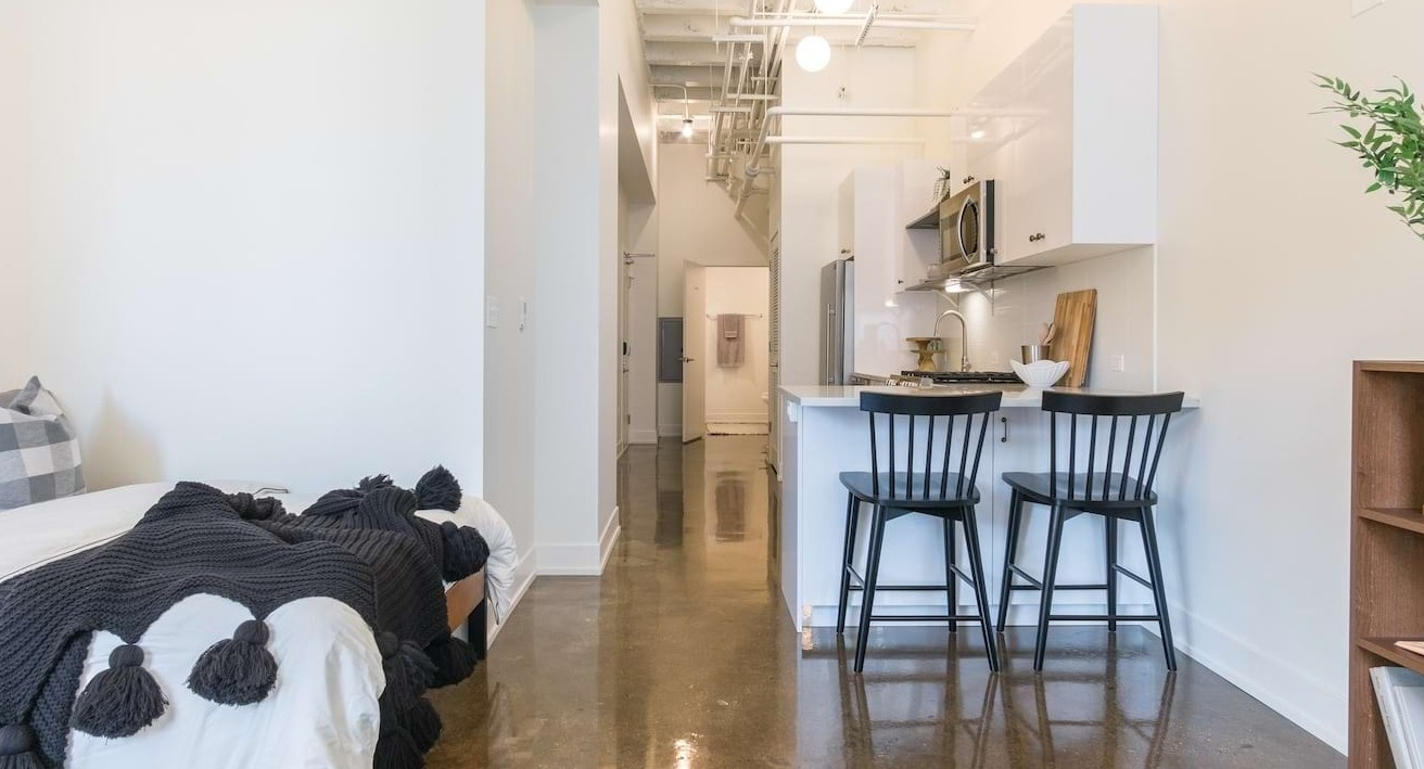 Studio apartment at The Alfred Apartments in Chicago, showcasing a compact kitchen with a breakfast bar and cozy bed