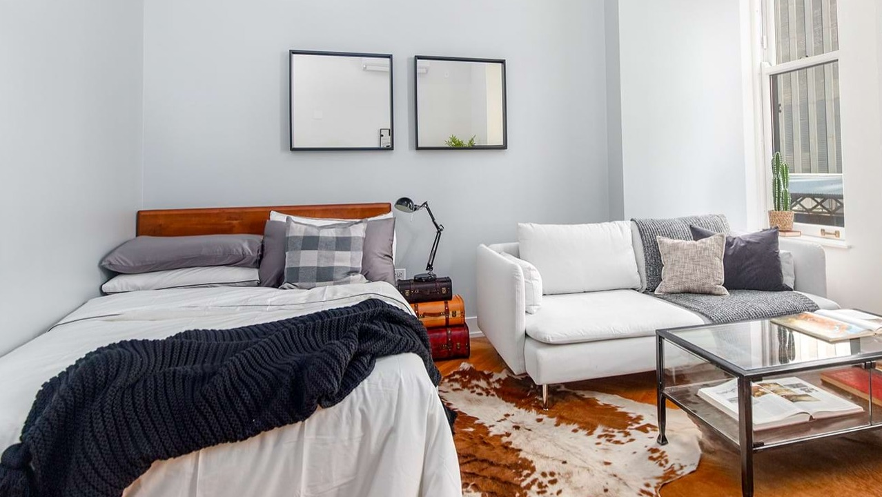 Studio apartment at The Alfred Apartments in Chicago, combining a comfortable bed, sofa, and living area with a large window