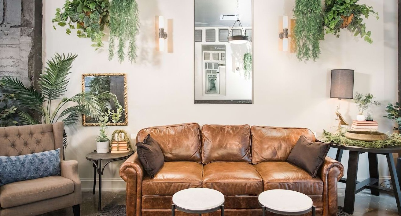 Stylish resident lounge at The Alfred Apartments in Chicago, featuring a leather sofa, hanging plants, and elegant decor