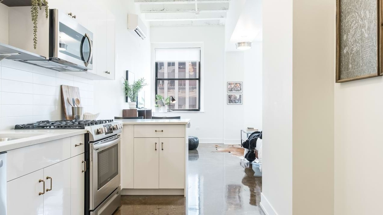 White galley kitchen at The Alfred Apartments in Chicago, featuring subway tile backsplash, stainless steel appliances, and polished concrete floors