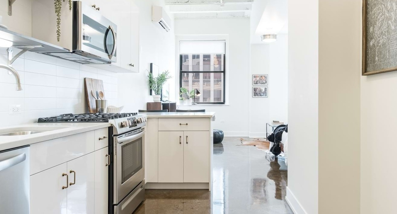 White galley kitchen at The Alfred Apartments in Chicago, featuring subway tile backsplash, stainless steel appliances, and polished concrete floors
