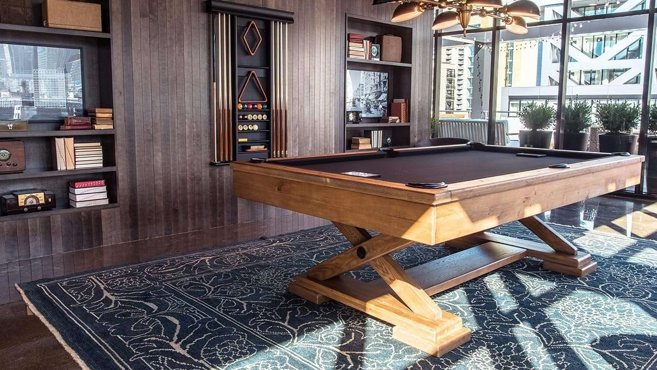 Stylish billiards room at The Ardus in Chicago, featuring a wooden pool table, comfortable seating, and city views through large windows