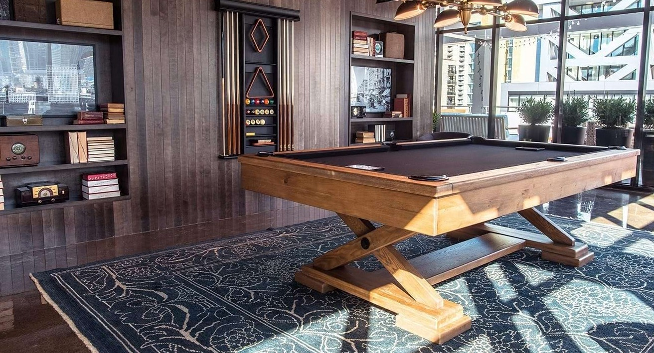Stylish billiards room at The Ardus in Chicago, featuring a wooden pool table, comfortable seating, and city views through large windows