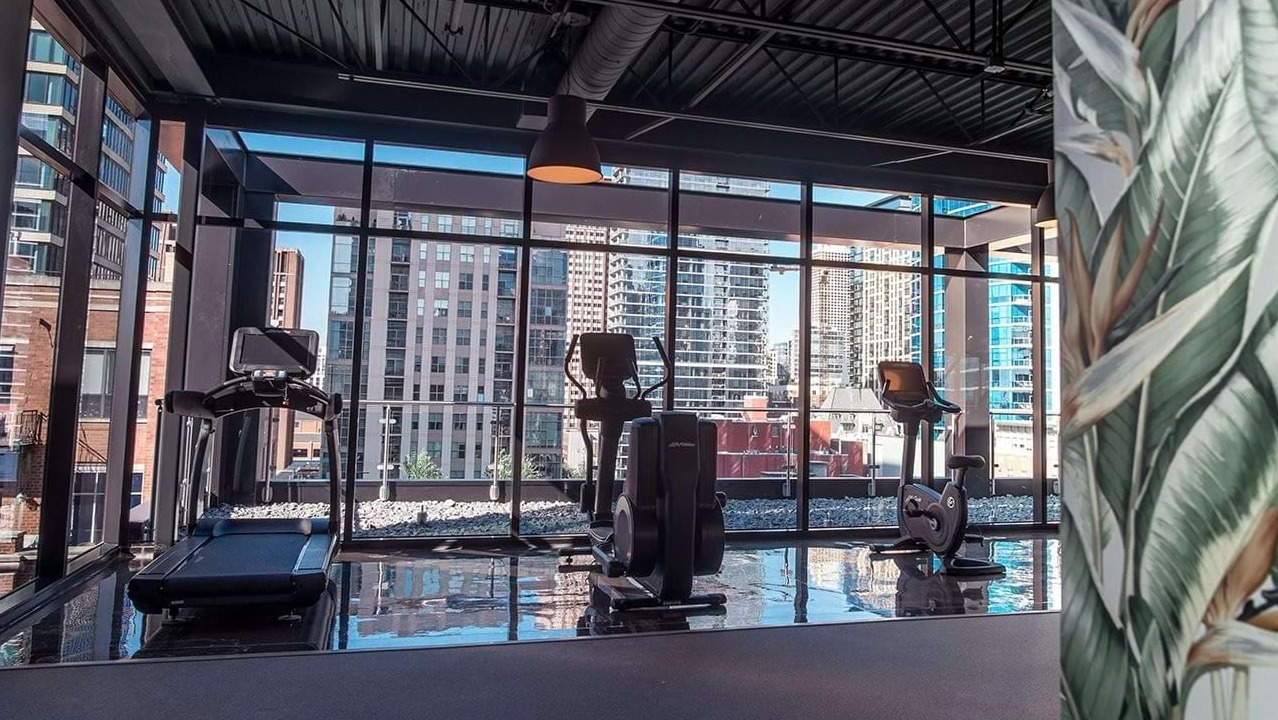Modern fitness center at The Ardus in Chicago, featuring cardio machines and large windows with urban views