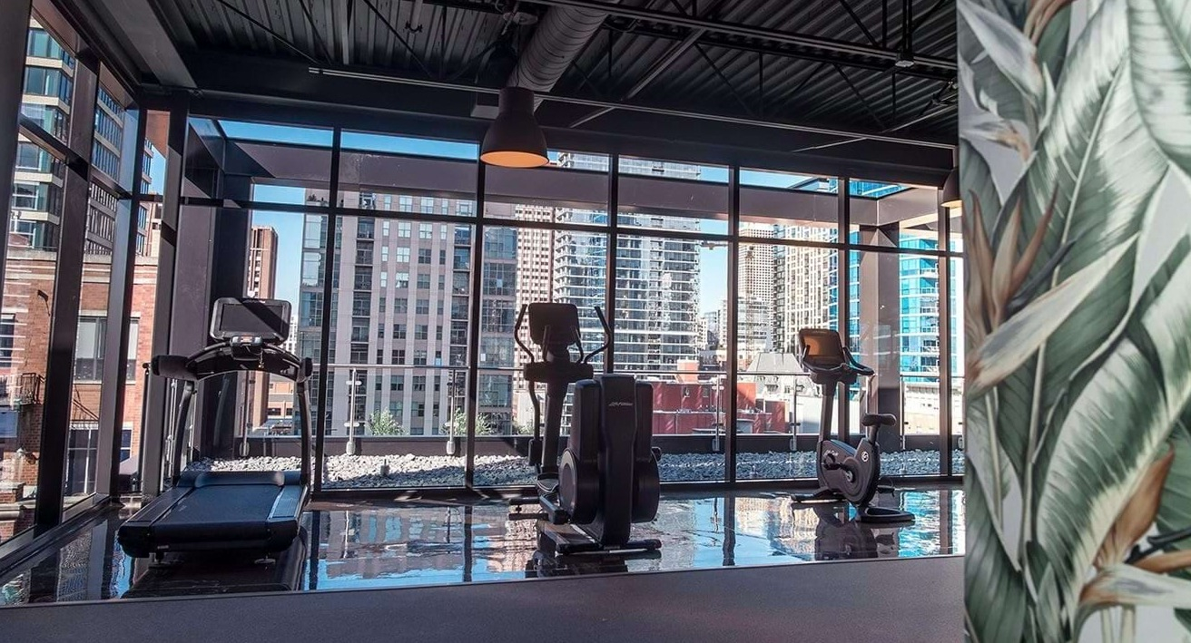Modern fitness center at The Ardus in Chicago, featuring cardio machines and large windows with urban views 