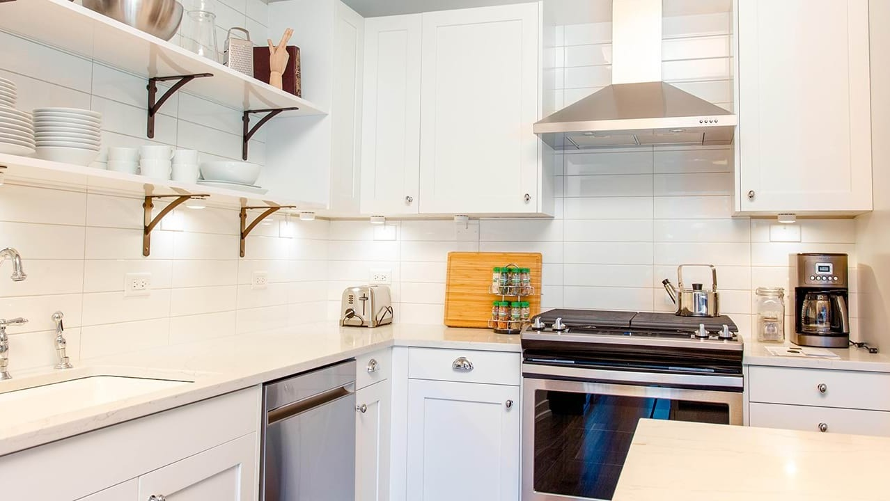 Gourmet apartment kitchen at The Ardus in Chicago, featuring white subway tile backsplash, stainless steel appliances, and open shelving