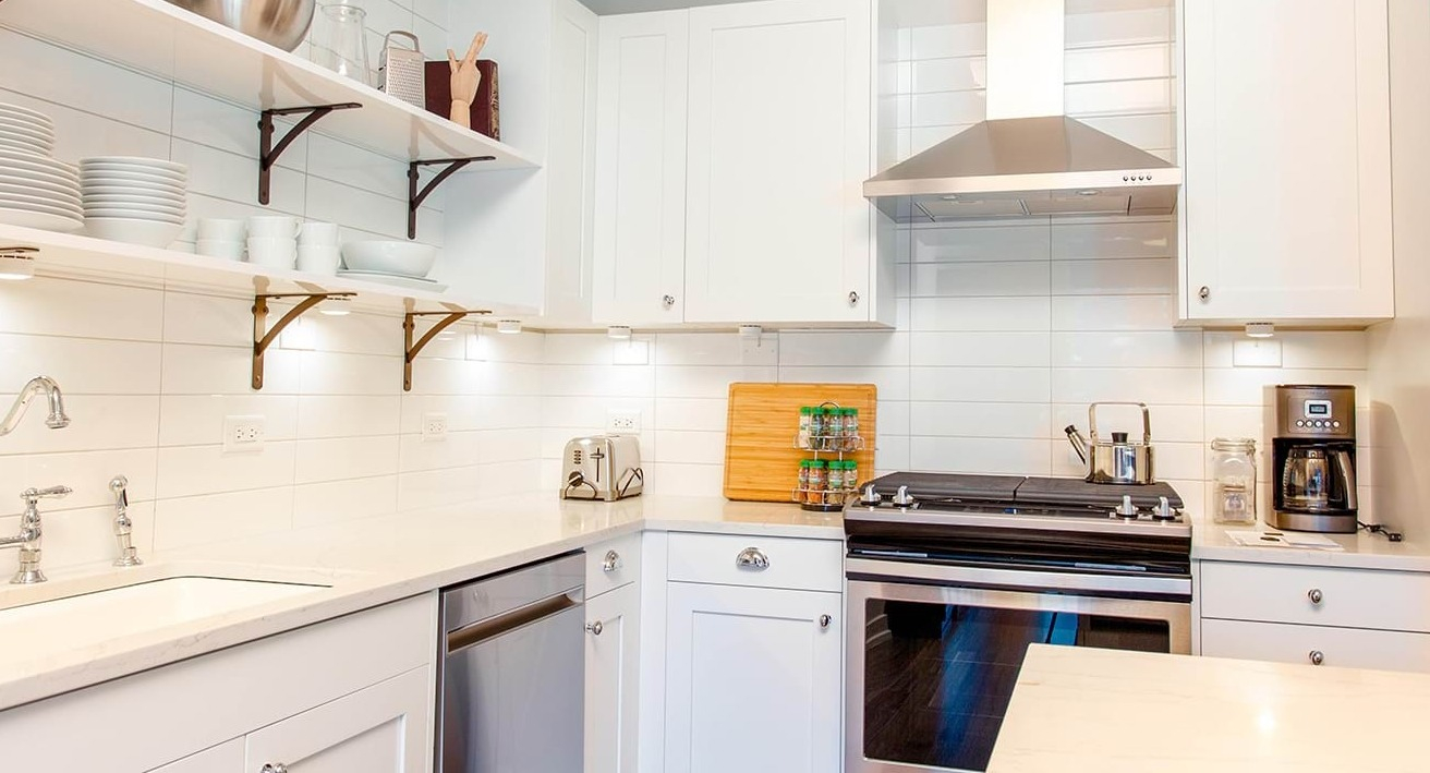 Gourmet apartment kitchen at The Ardus in Chicago, featuring white subway tile backsplash, stainless steel appliances, and open shelving