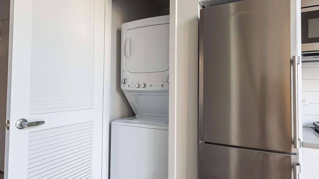 Convenient in-unit laundry closet at The Ardus in Chicago, featuring a stacked washer and dryer next to the kitchen